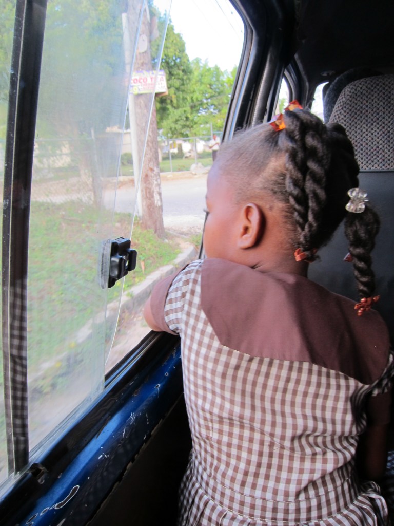 Looking to the future. This girl is acting as a "loader or ducta" man on the bus to town. 